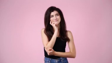 Pembe arka planda düşünceli yüz ifadesi olan bir kızın 4K videosu. Fikirleri olan kız kavramı.