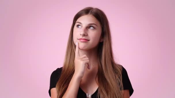 ピンクの背景に思慮深い表情の女の子の4K動画 アイデアを持つ少女の概念 — ストック動画