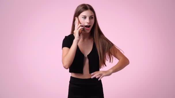 ピンクの背景で電話で話している1人の女の子の4Kビデオ 感情の概念 — ストック動画