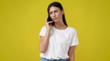 Sarı arka planda telefonla konuşan bir kızın 4K videosu. Duyguların kavramı.