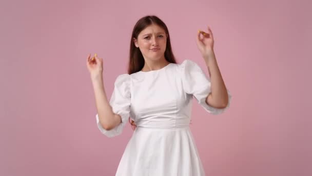 4K慢动作视频 一个女孩指着相机 用大拇指在粉色背景上显示 情绪的概念 — 图库视频影像
