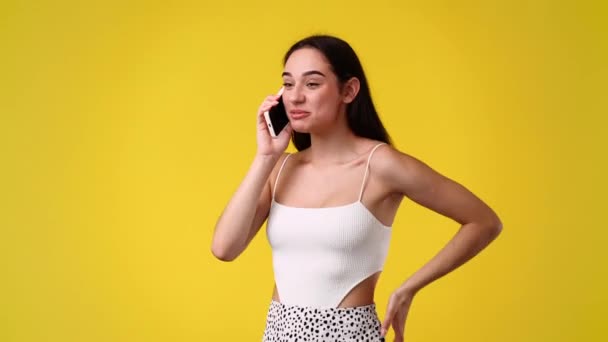 4K慢镜头 一个女孩在黄色背景下通过电话交谈 情绪的概念 — 图库视频影像