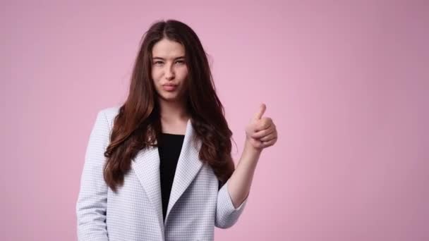 4K慢镜头 一个女孩指着右边 在粉色背景上伸出大拇指 情绪的概念 — 图库视频影像