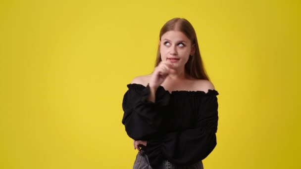 黄色の背景に思慮深い顔の表情を持つ少女の4Kスローモーションビデオ アイデアを持つ少女の概念 — ストック動画