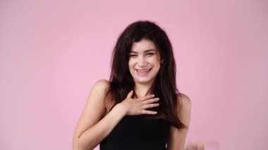 Pembe arka planda gülen bir kızın 4K yavaş çekim videosu. Duyguların kavramı.
