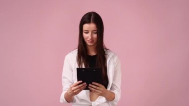 Pembe arka planda not defteri olan bir kızın 4K videosu. Duyguların kavramı.