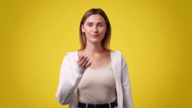 Sarı arka planda hava öpücüğü gönderen bir kızın 4K yavaş çekim videosu. Aşk duygusu kavramı.