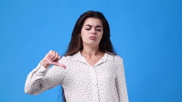 青色の背景に親指を示す1人の少女の4Kビデオ 負の感情の概念 — ストック動画