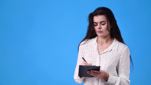青い背景の上にいくつかのメモを取る1人の女の子の4Kビデオ 感情の概念 — ストック動画