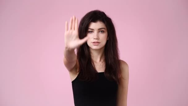 ピンクの背景の上に停止標識を示す1人の女の子の4Kビデオ 感情の概念 — ストック動画