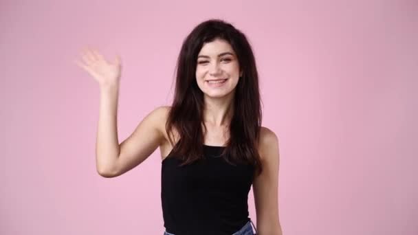 ピンク色の背景にこんにちはを振ってかわいい女の子の4K動画 感情の概念 — ストック動画