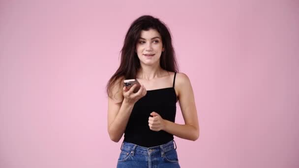 ピンクの背景で電話で話している1人の少女の4Kスローモーションビデオ 感情の概念 — ストック動画