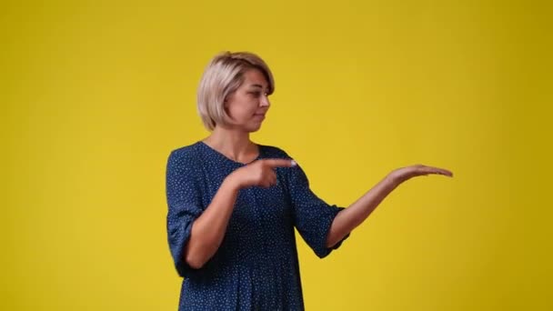 Video One Woman Pointing Right Showing Thumb Yellow Background Concept — Vídeos de Stock