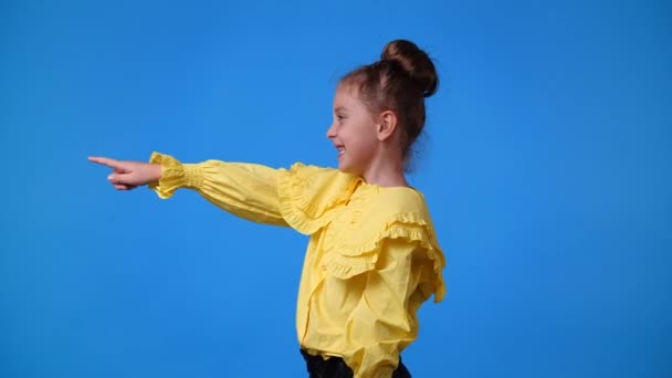 Slow Motion Video One Girl Pointing Left Smiling Blue Background — Stock Video