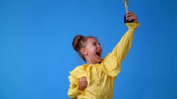 青い背景の上に賞を保持する小さな女の子の4Kスローモーションビデオ 感情の概念 — ストック動画