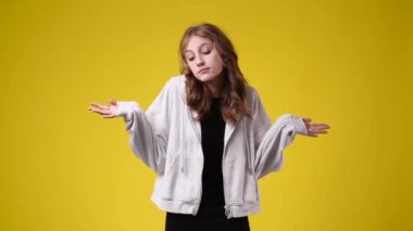 Sarı arka planda düşünceli yüz ifadesi olan bir kızın 4K yavaş çekim videosu. Fikirleri olan kız kavramı.