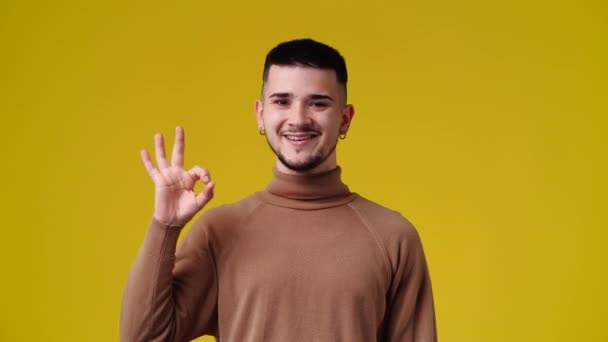 黄色の背景にOkサインを示す1人の男の4Kスローモーションビデオ 感情の概念 — ストック動画