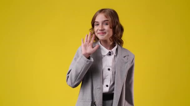 黄色の背景にこんにちはを振ってかわいい女の子の4Kスローモーションビデオ 感情の概念 — ストック動画