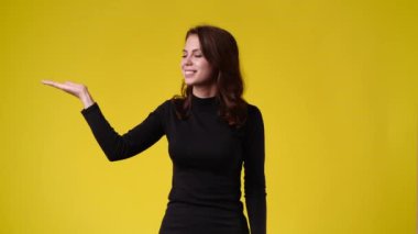 4k video of one girl pointing at left over yellow background. Concept of emotions.