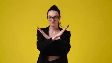 4k slow motion video of one girl with crossed hands on yellow background. Concept of negative emotion.