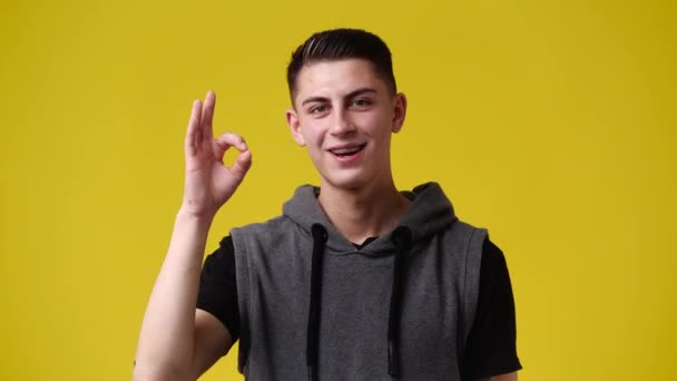 黄色の背景にOkサインを示す1人の男の4Kスローモーションビデオ 感情の概念 — ストック動画