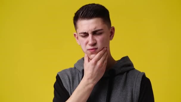 黄色い背景に顎に触れた男の4Kスローモーションビデオ 感情の概念 — ストック動画
