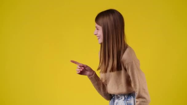 Slow Motion Video One Girl Pointing Left Laughing Yellow Background — Stockvideo
