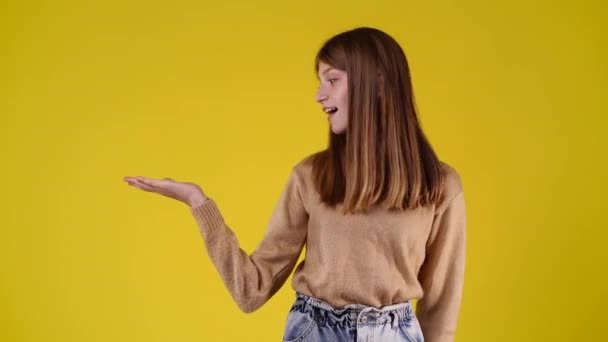 Slow Motion Video One Girl Pointing Left Yellow Background Concept — Vídeos de Stock