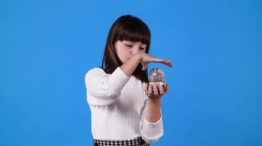 4k slow motion video of one girl with Christmas ball over blue background. Concept of emotions.