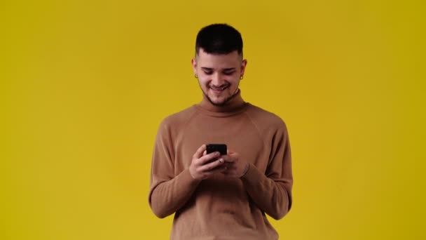 黄色の背景の上に電話を使用して1人の男の4Kスローモーションビデオ 感情の概念 — ストック動画