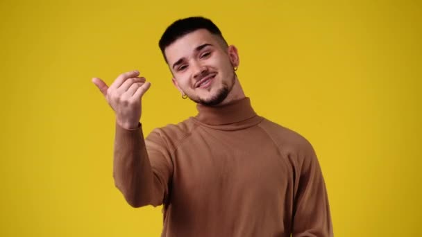 ハンサムな男のジェスチャーの4Kビデオはここに黄色の背景に来ます 感情の概念 — ストック動画
