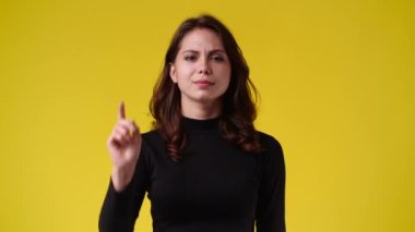 Sarı arka planda parmağı olmayan bir kızın 4K yavaş çekimi. Duyguların kavramı.