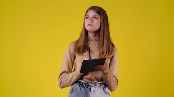 4K慢镜头 一个女孩在黄色背景下记下一些笔记 情绪的概念 — 图库视频影像