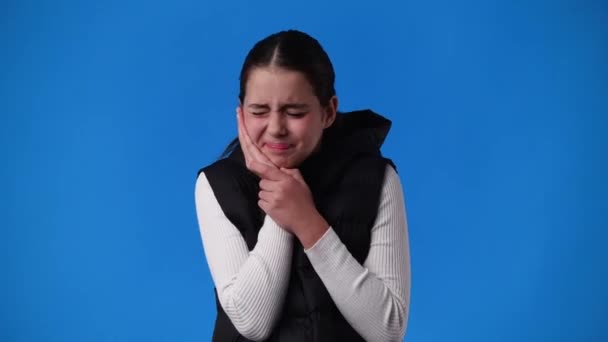 青い背景に歯痛のある1人の女の子の4Kビデオ 病気の少女の概念 — ストック動画