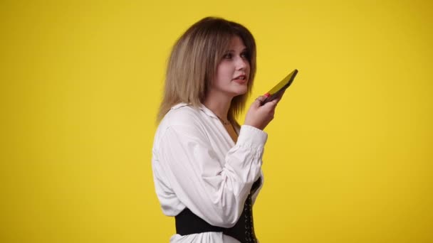 一个女孩在黄色背景下通过电话交谈的4K视频 情绪的概念 — 图库视频影像