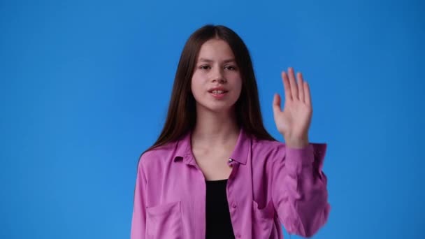 青い背景の上に停止標識を示す1人の少女の4Kスローモーションビデオ 感情の概念 — ストック動画