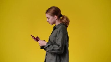 4k slow motion video of side view of one girl sending messages on yellow background. Concept of emotions.