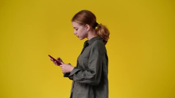 黄色の背景にメッセージを送る1人の少女の横ビューの4Kスローモーションビデオ 感情の概念 — ストック動画
