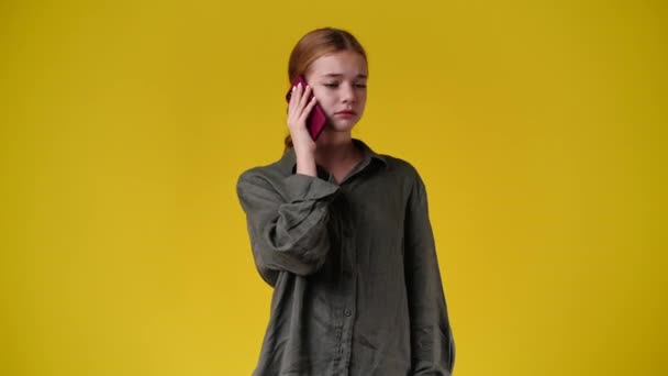 黄色の背景で電話で話している1人の少女の4Kスローモーションビデオ 感情の概念 — ストック動画