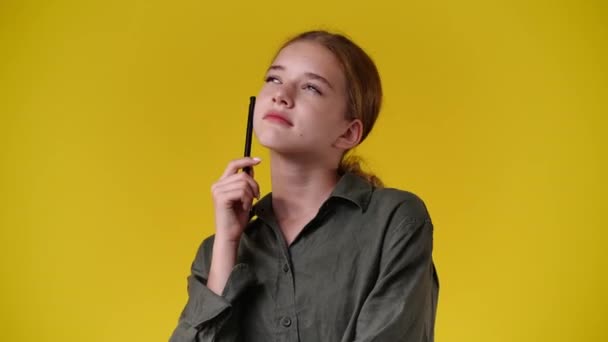 黄色の背景に思慮深い顔の表情を持つ少女の4Kスローモーションビデオ アイデアを持つ少女の概念 — ストック動画