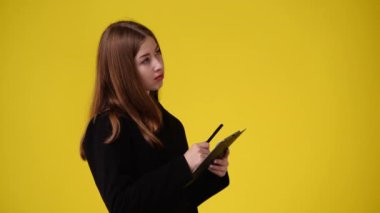 4k slow motion video of one girl taking notes over yellow background. Concept of emotions.