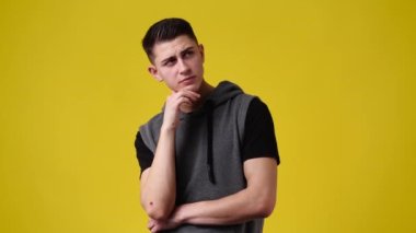 4k slow motion video of one man with thoughtful facial expression on yellow background. Concept of man with ideas.