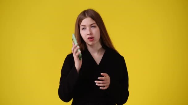 黄色の背景で電話で話している1人の少女の4Kビデオ 感情の概念 — ストック動画