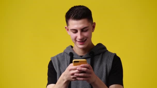 1人の男の4Kスローモーションビデオ黄色の背景色の上に電話を使用して 感情の概念 — ストック動画