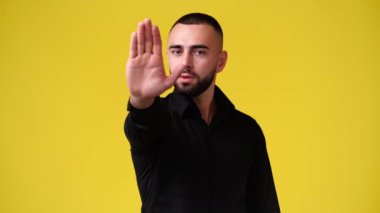 4k slow motion video of one man showing stop sign over yellow background. Concept of emotions.
