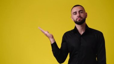 4k slow motion video of one man pointing at left and showing thumb up on yellow background. Concept of emotion.