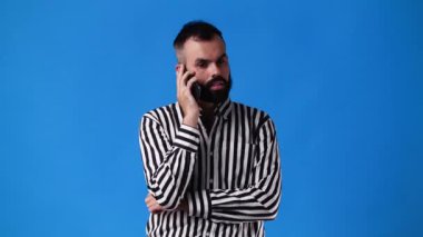 4k slow motion video of one talking over the phone on blue background. Concept of emotions.