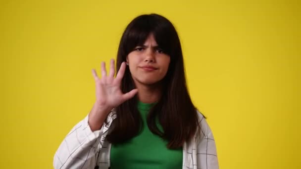 1人の少女の4Kスローモーションビデオジェスチャー黄色の背景で停止します 感情の概念 — ストック動画