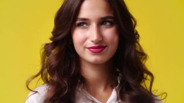 4k slow motion video of one girl looking side to side over yellow background. Concept of emotions.