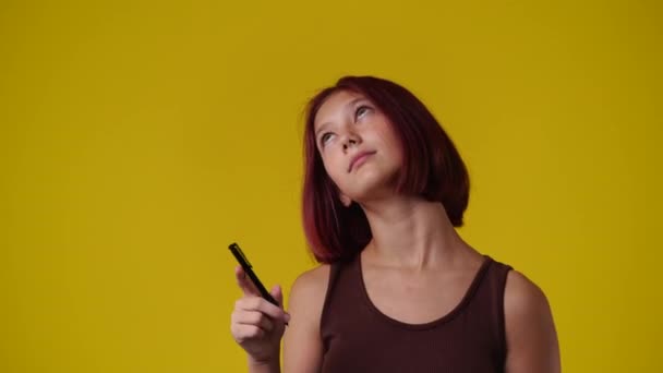 片手にペンで何かを考えている1人の女の子の4Kスローモーションビデオ 感情の概念 — ストック動画